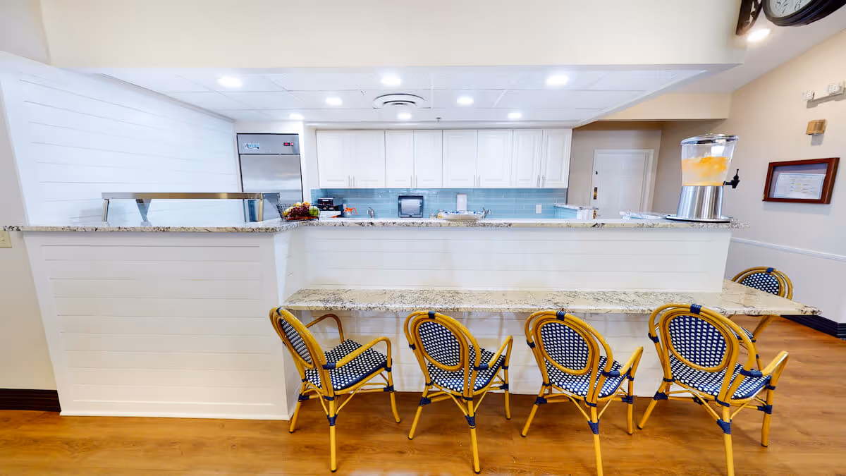 Bright dining/serving counter with four woven bistro chairs facing a white service bar and kitchen area.