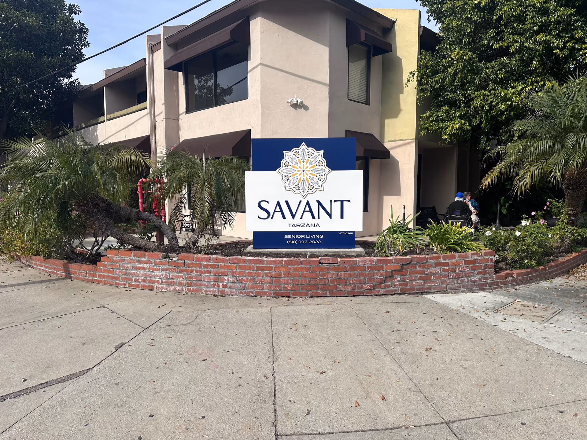Exterior view of Savant Tarzana senior living with entrance sign and landscaping.