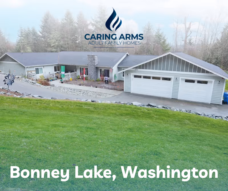 Exterior view of Caring Arms Adult Family Homes building with logo and green lawn.