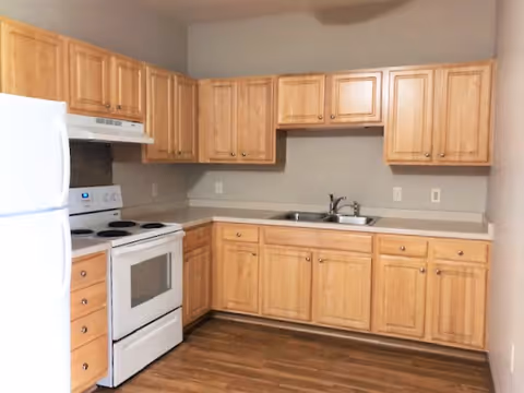 Kitchen with light wood cabinets, a white refrigerator and stove, a double-basin sink, and wood-look flooring.