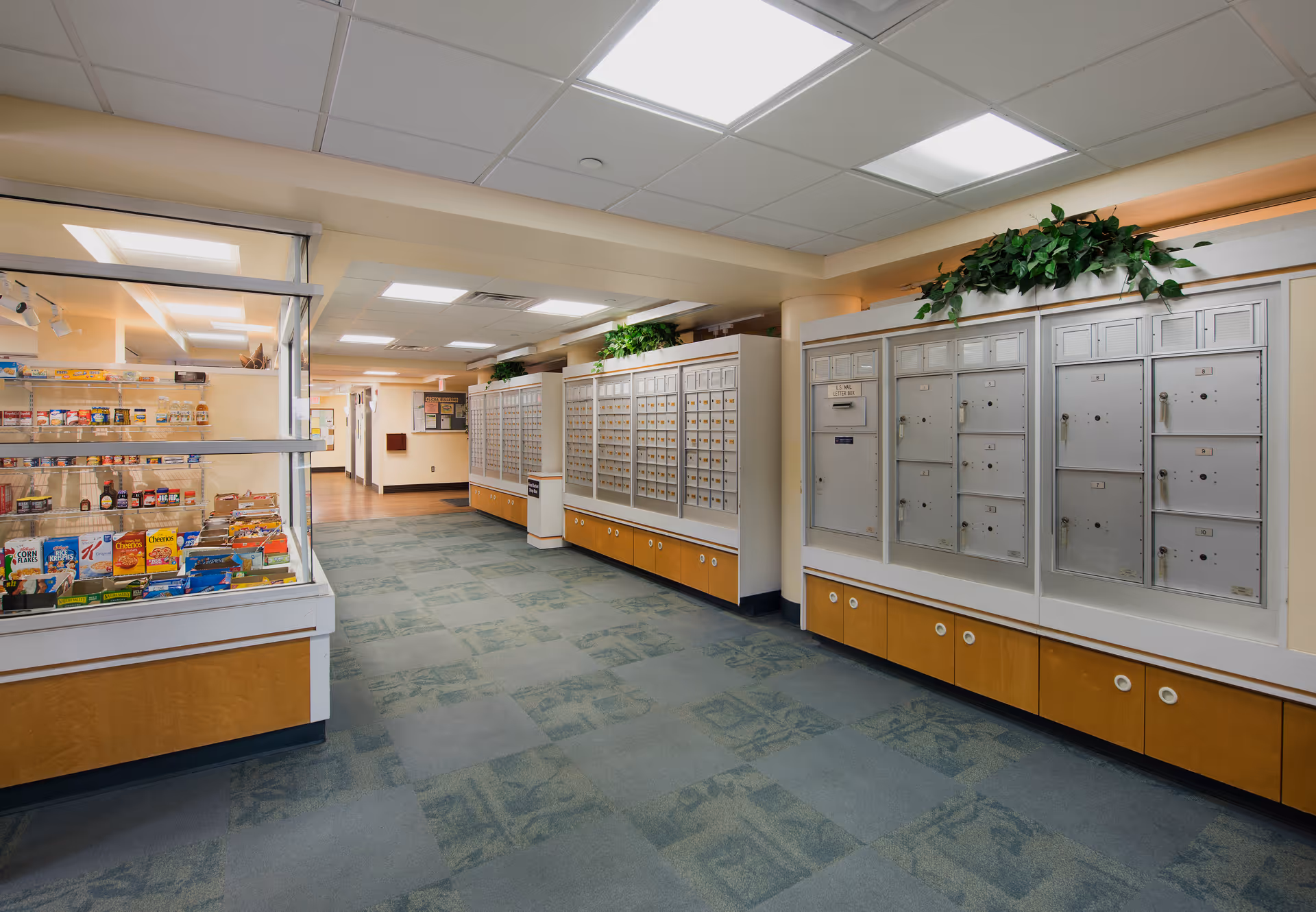 Interior hallway featuring rows of mailboxes along the wall and a small convenience store display case.