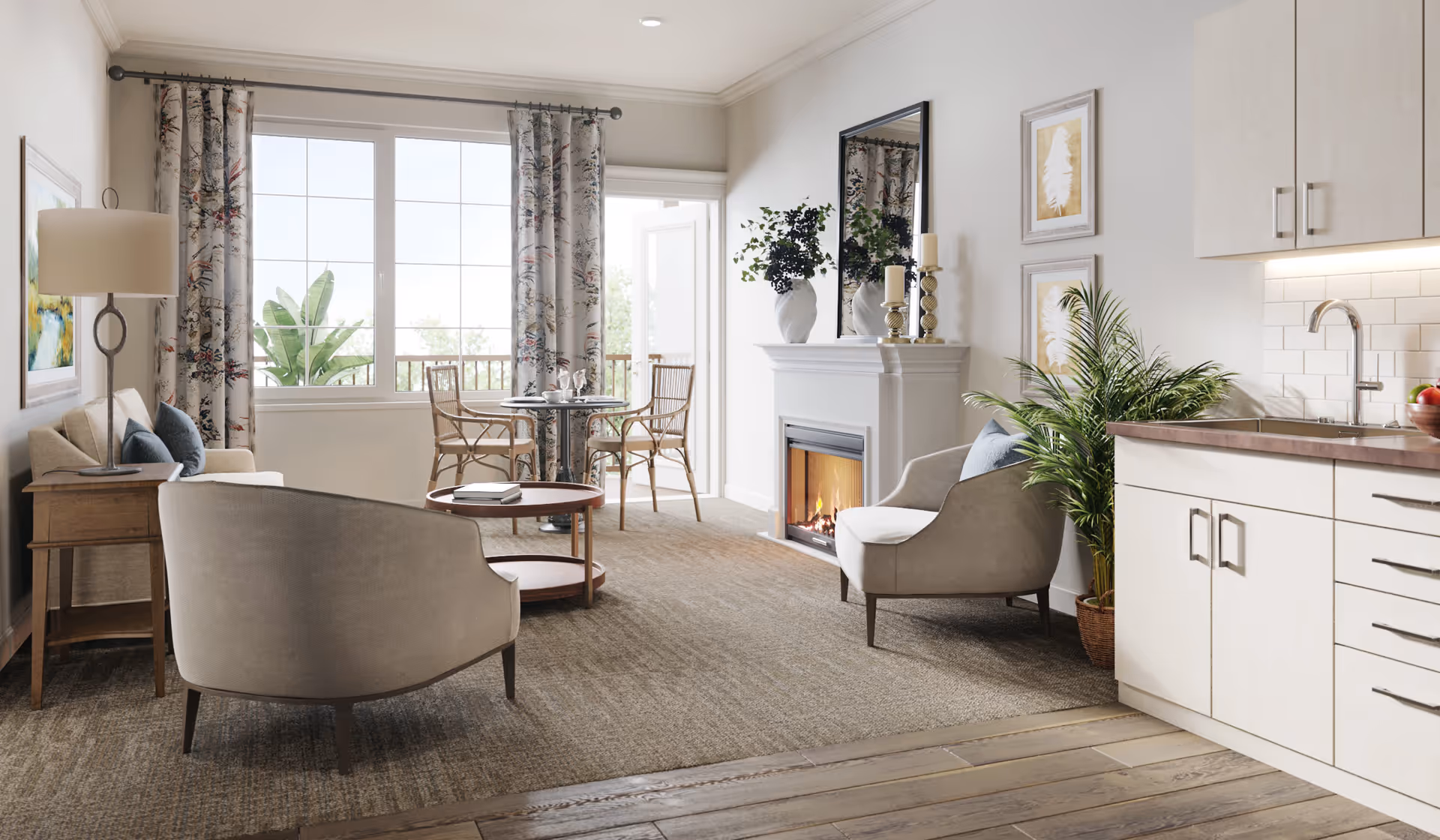 Bright open living area with chairs and a sofa facing a fireplace, a small dining table by large windows, and a kitchenette to the right.