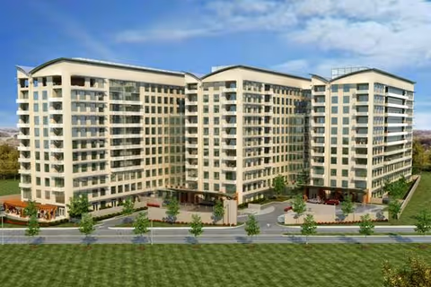 Front view of a large multi-wing, multi-story cream-colored building with balconies and landscaped driveways.