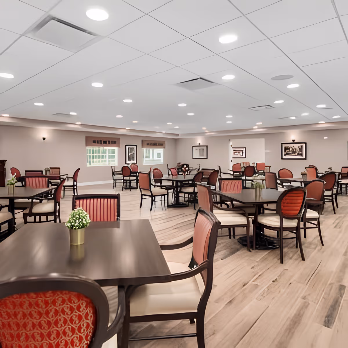 Spacious dining room with multiple tables and chairs, wood-look flooring, and recessed ceiling lighting.