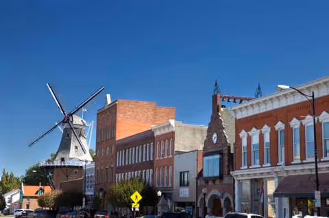 Historic downtown street in Pella with brick fronts and a windmill against a blue sky.