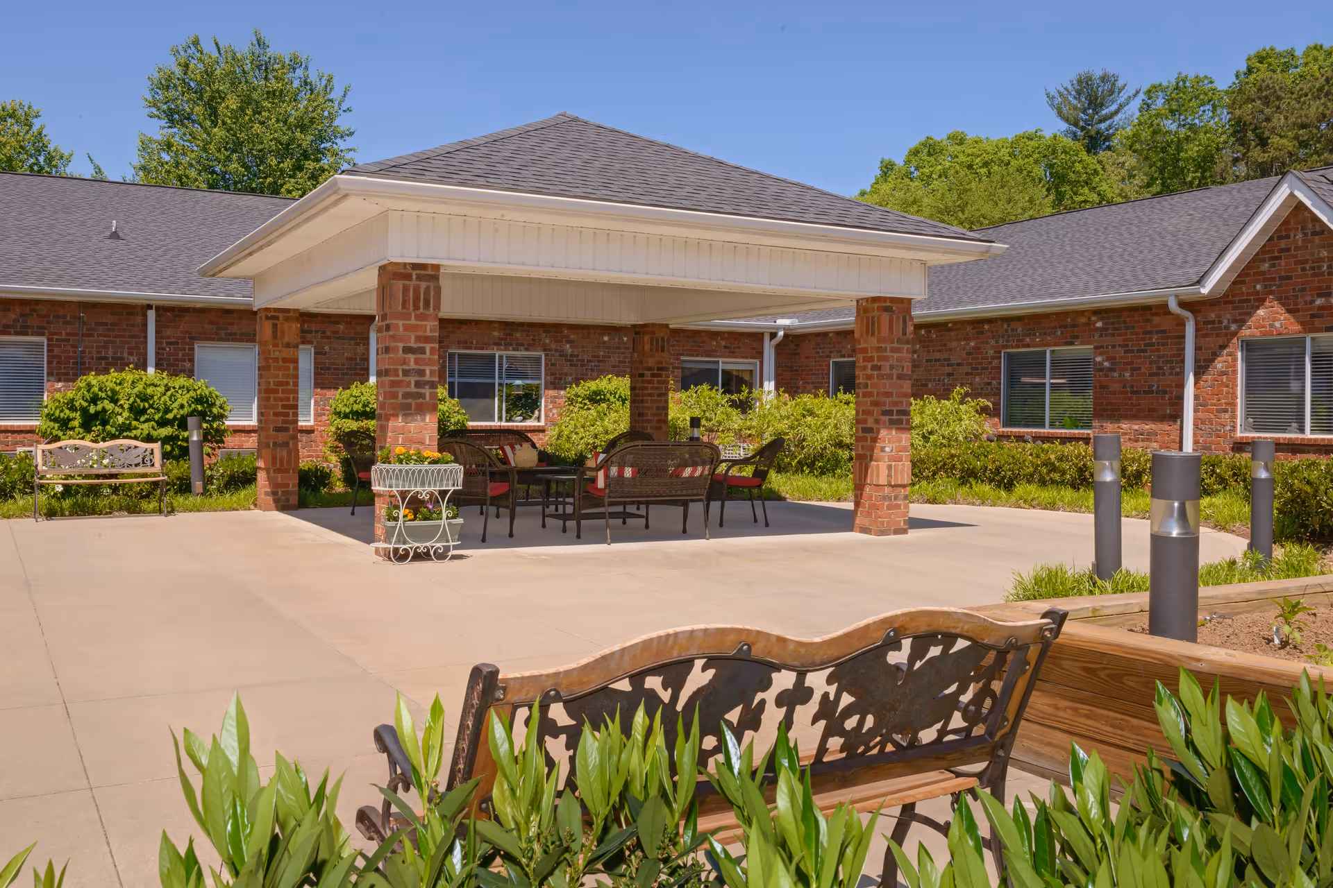 Covered outdoor courtyard with a pavilion, seating, and surrounding brick building under a clear blue sky.