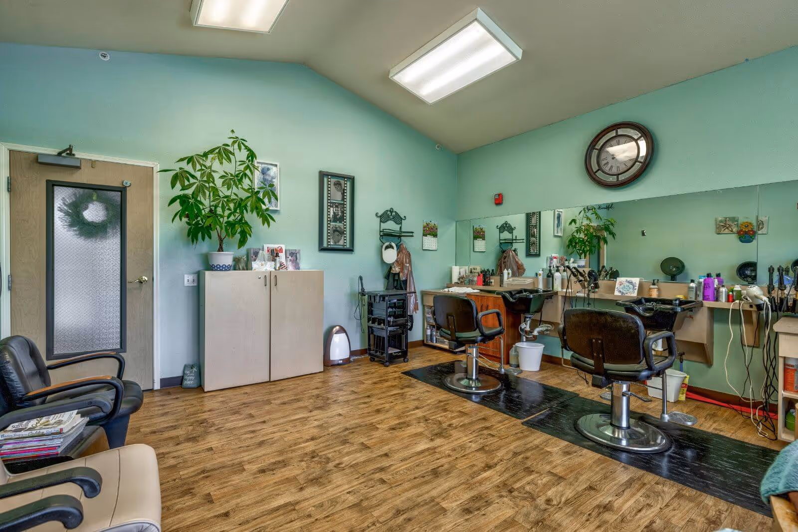 Interior salon with styling chairs, mirrors, and hairdressing stations in a mint-green room.