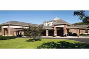 Exterior view of Sugar Creek Care Center, brick building with manicured lawn and covered entrance.