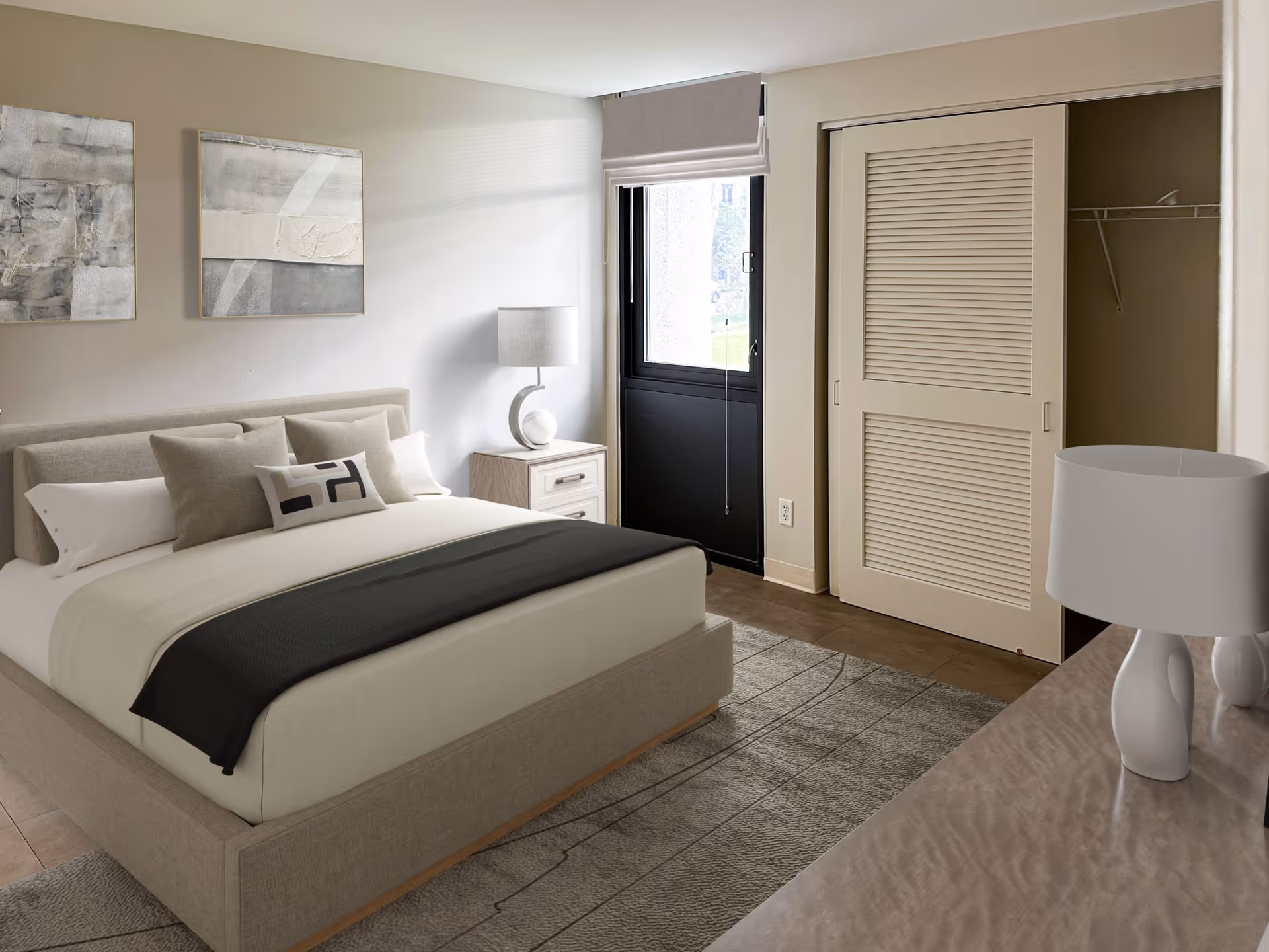 Neutral-toned bedroom with a made bed, bedside table and lamp, window, and an open closet with sliding doors.