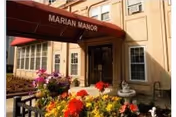 Entrance of Marian Manor with a red awning and colorful flower beds in front.