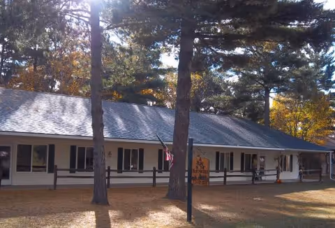 Single-story building with a covered front porch, trees, and a sign promoting Dianne's Home in Northwoods.