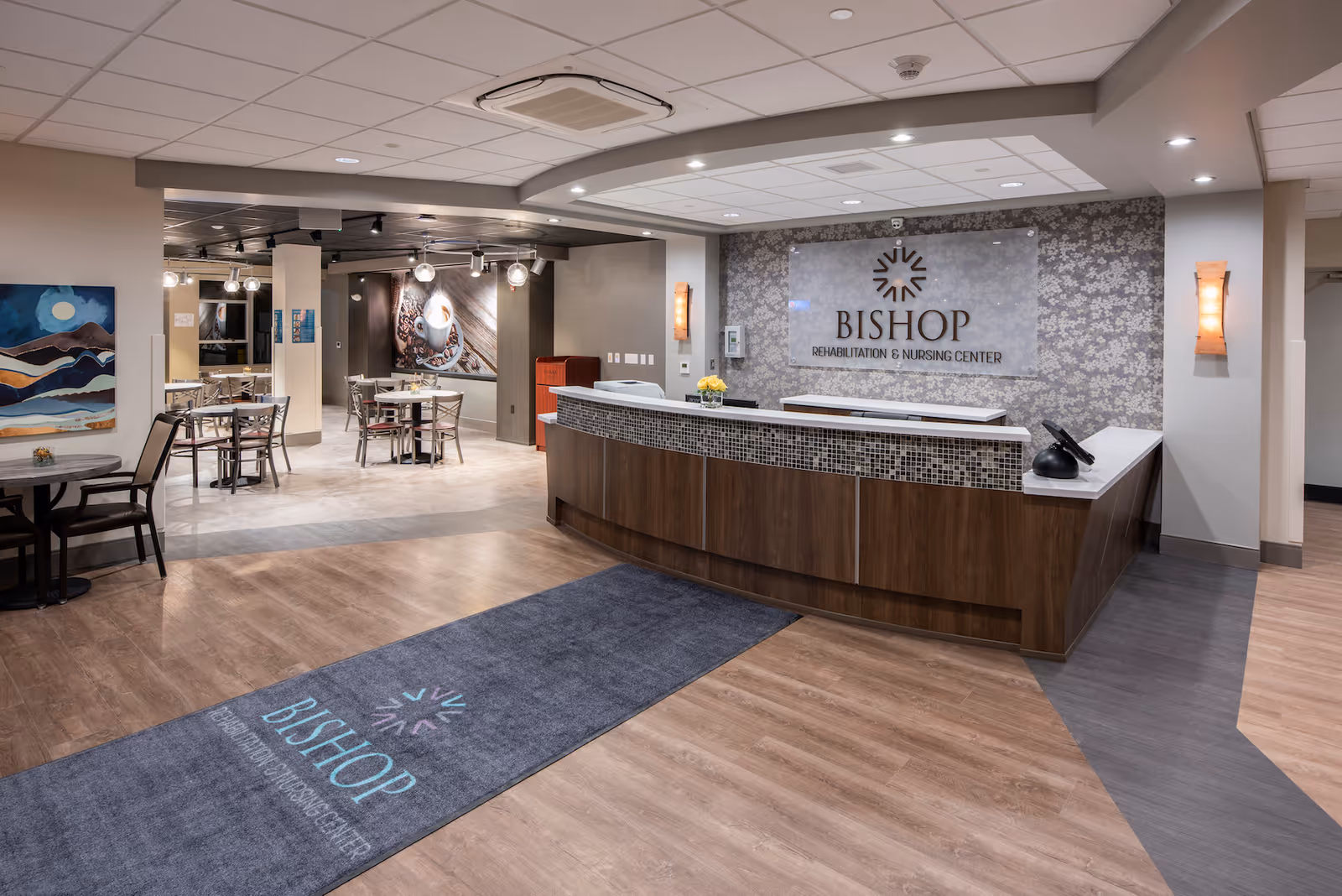 Reception area of Bishop Rehabilitation & Nursing Center showing the front desk, seating area, and a branded floor mat.