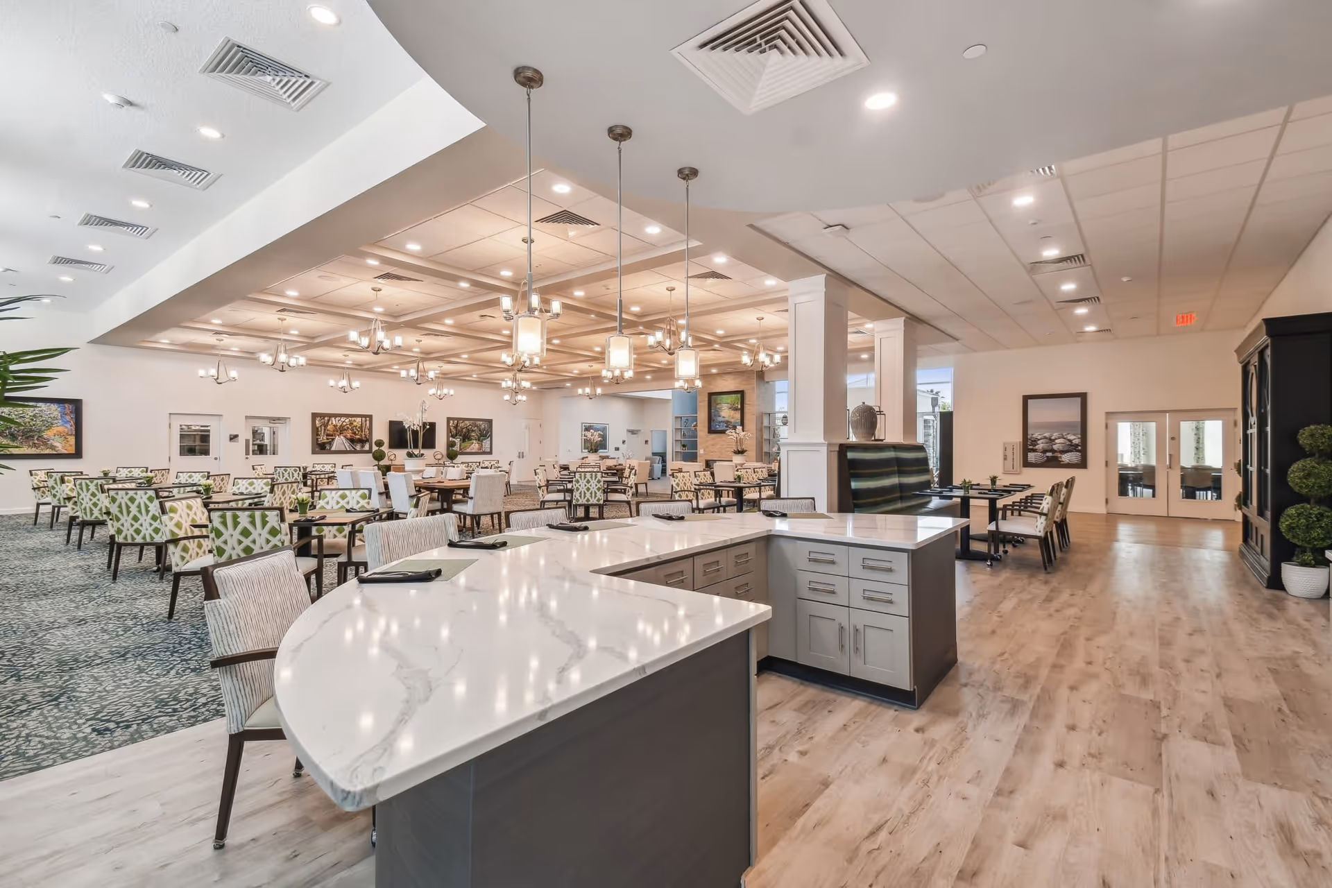 Spacious, well-lit communal dining area with multiple tables and chairs and a central marble-topped serving counter.