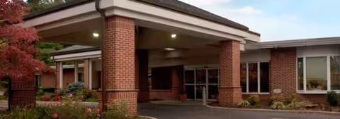 Brick building entrance with a covered drop-off at Coffman Nursing Home.