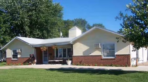 Front exterior of a single-story building with brick lower wall and porch.