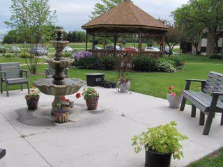Outdoor courtyard featuring a fountain, gazebo, benches, and potted plants.