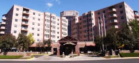 Large multi-story Brookdale University Park senior living building with entrance canopy and flags.