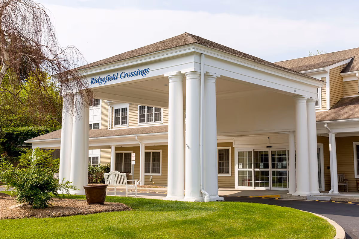 Front entrance of Ridgefield Crossings with white classical columns and a covered porte-cochère leading to glass doors.