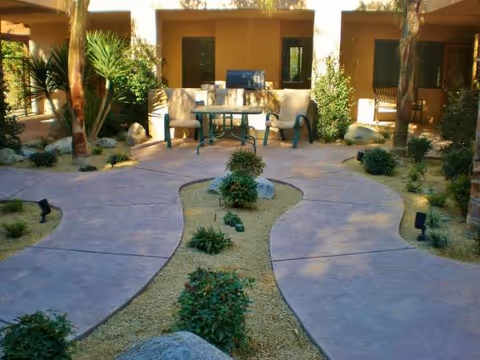 Outdoor courtyard at La Bella Gardens with winding concrete paths, desert landscaping, and seating.