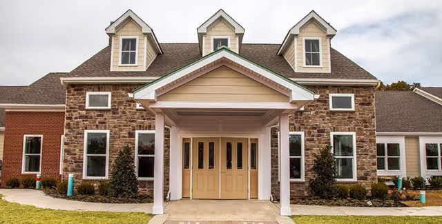 Front entrance of Mullica Gardens Assisted Living, a stone-and-brick building with a covered porch.
