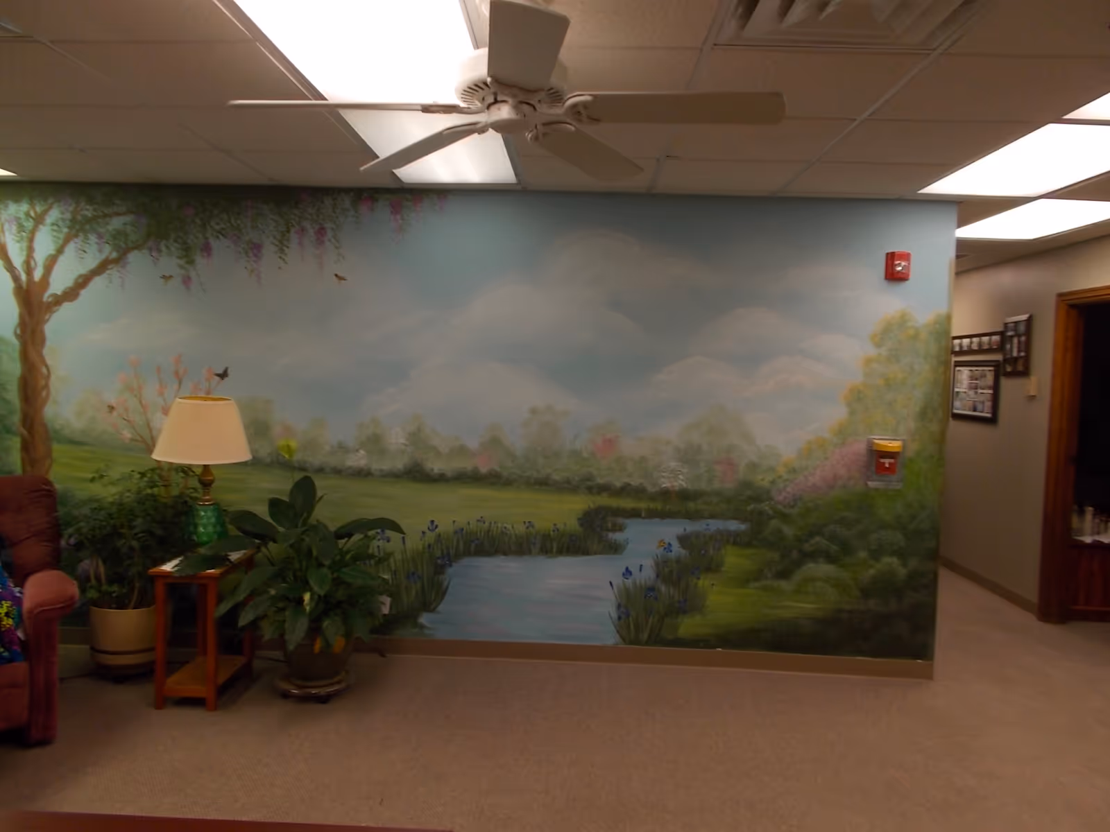 Interior lounge area with mural wall, ceiling fan, plants, and seating.