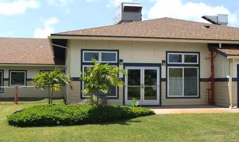 Front exterior of Kauai Care Center with glass doors, windows, and a green lawn.