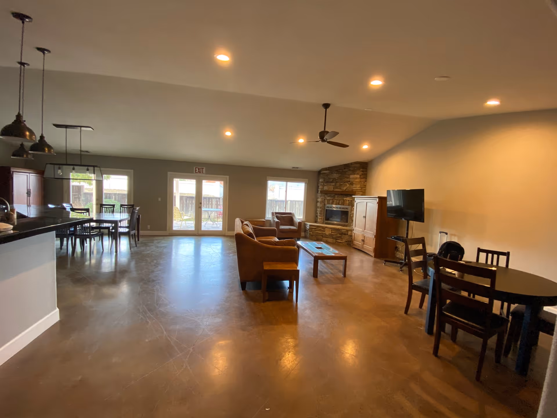 Spacious senior living common area with sofas, fireplace, TV, dining table, and kitchen counter.