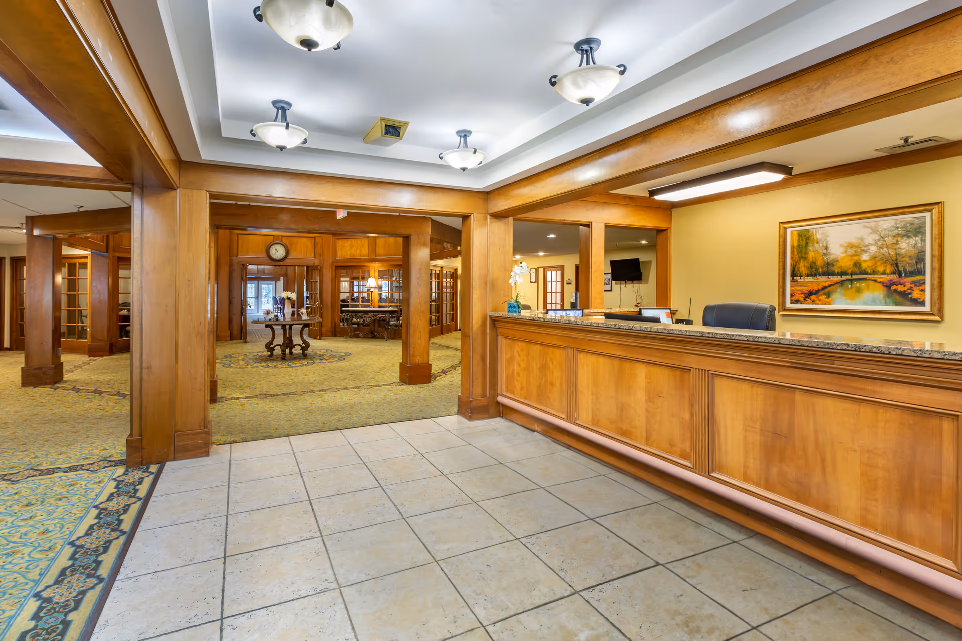 Reception desk and lobby area with wooden columns, tiled floor, and a central display table.