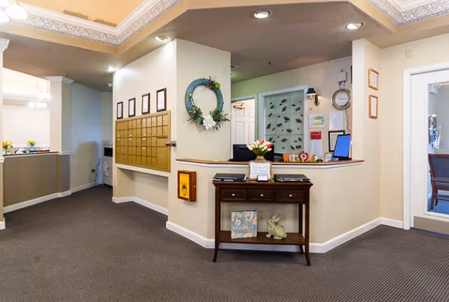 Reception area with mailboxes, a check-in desk, and a console table decorated with flowers and a wreath.