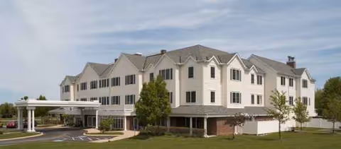 Three-story assisted living building with a covered entrance and manicured lawn.