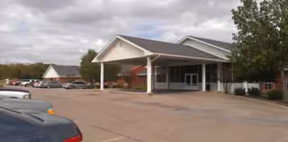 Front view of Marine Creek Nursing & Rehabilitation with a covered entrance and parking lot.