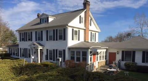 Two-story white manor-style senior living facility with a front porch.