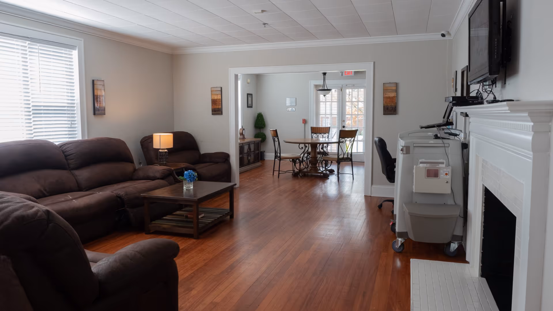 Cozy living room with brown leather sofas, a coffee table, and a medical cart.