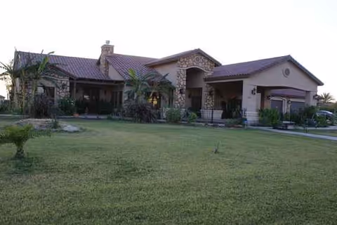 Single-story senior living facility with stone facade, arched entrance, and manicured lawn.