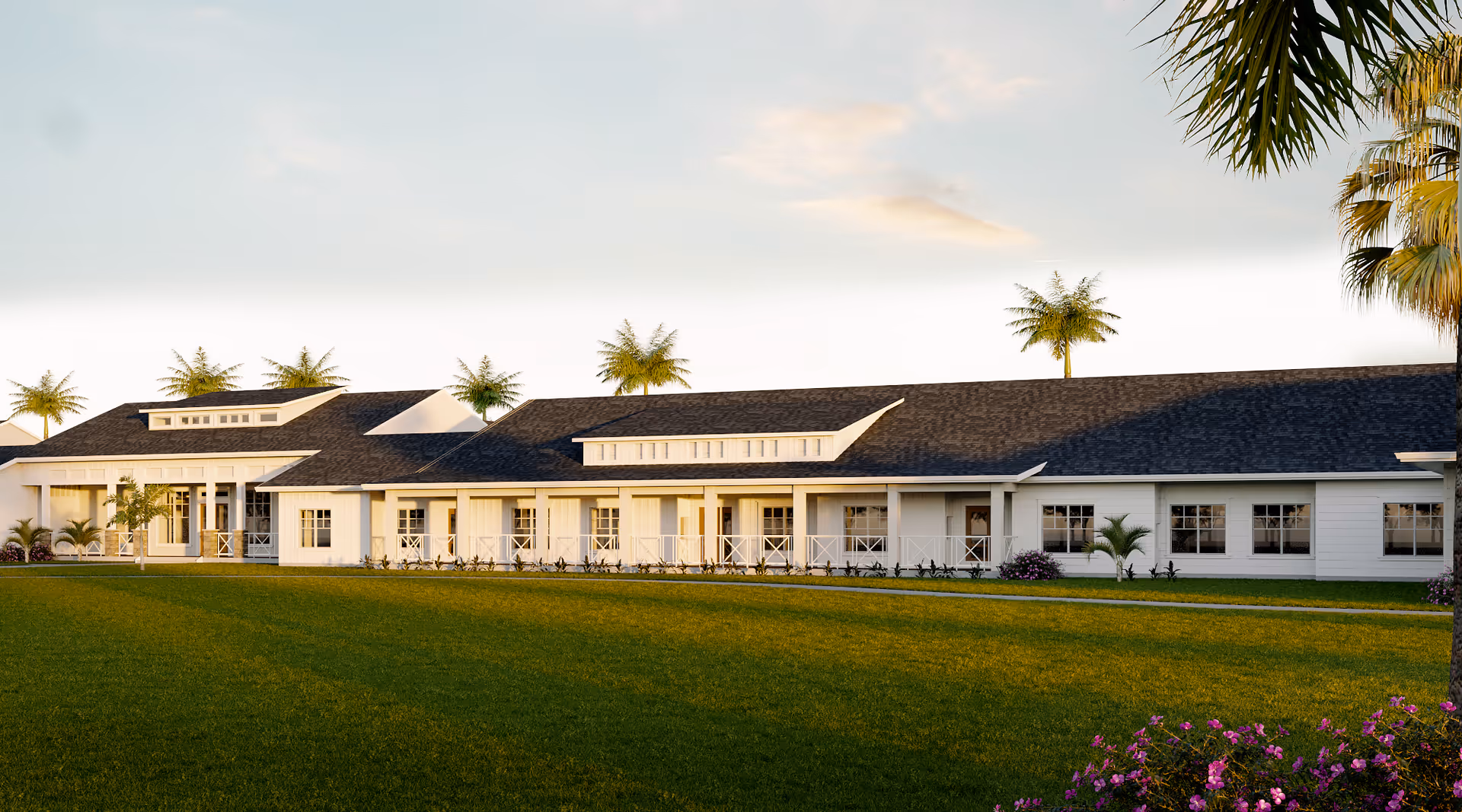 Long white single-story senior living building with a wide green lawn and palm trees under a clear sky.