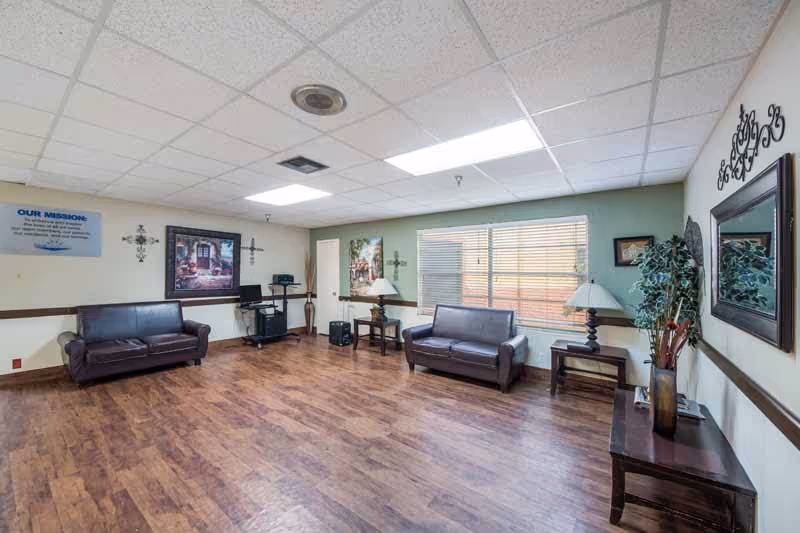 Interior view of a lounge area in a senior living facility with two couches, a table, and decorative elements.
