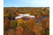 Aerial view of a multi-wing healthcare building surrounded by trees with autumn foliage.