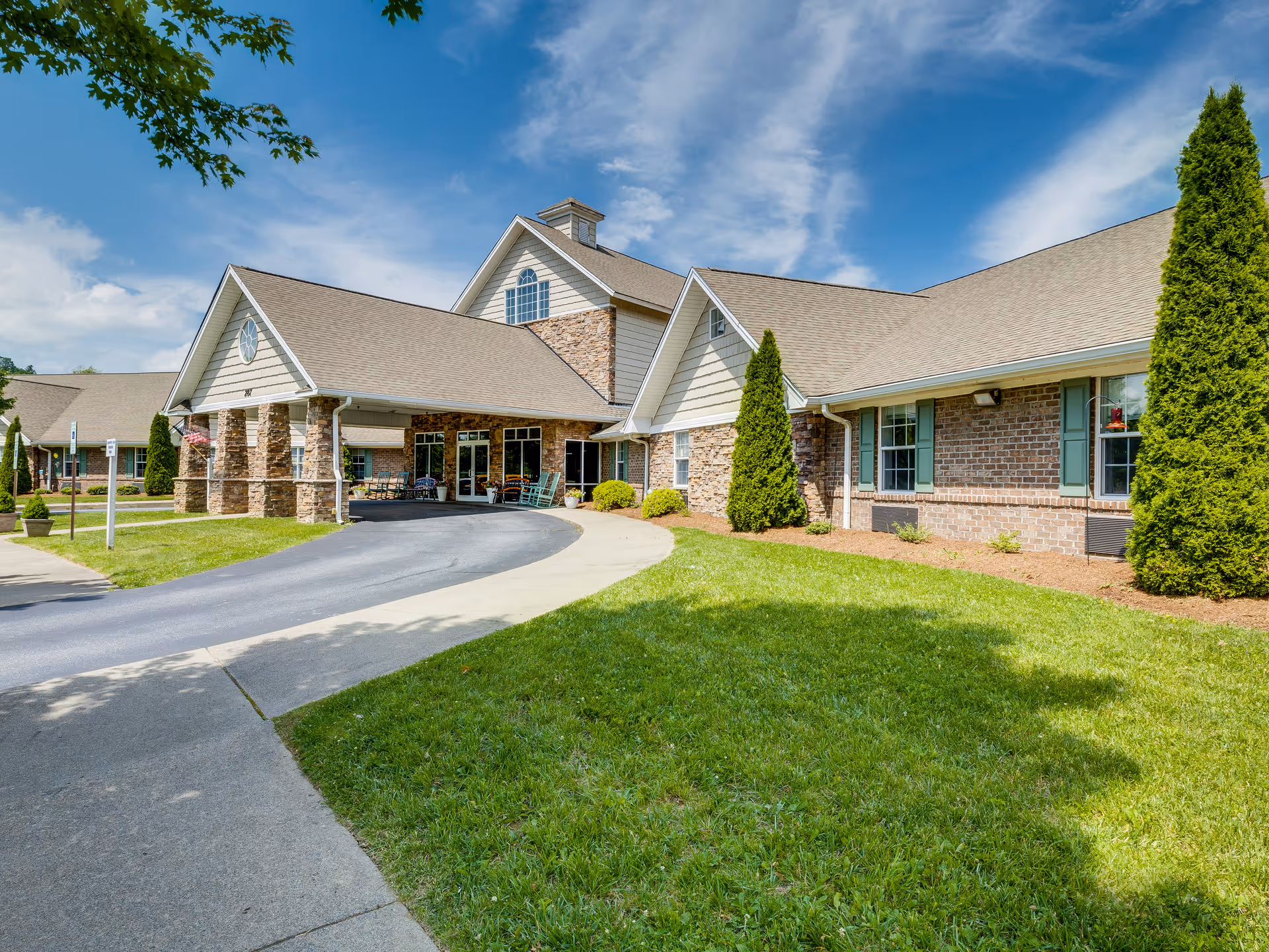 Exterior view of Deerfield Ridge Assisted Living building with curved driveway and green lawn