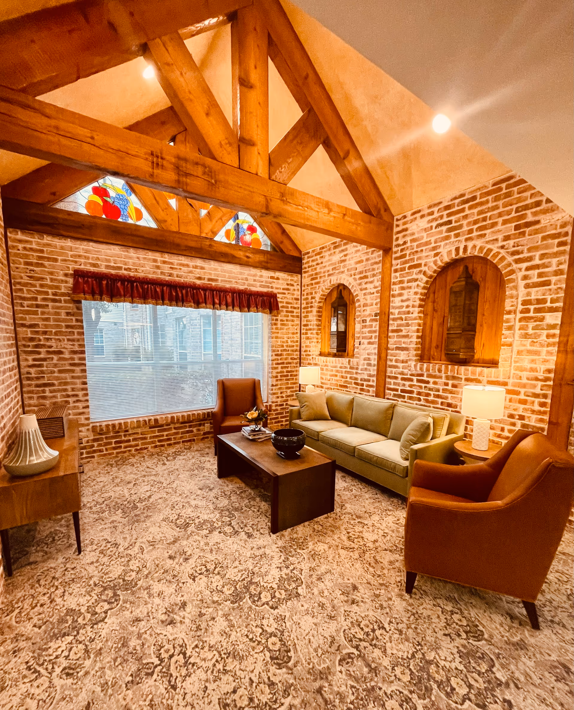 Cozy living room with exposed wooden beams, brick walls, a sofa, two armchairs and a coffee table.