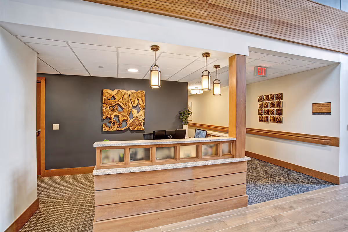 Reception desk and lobby area with pendant lights, decorative wall art, and a hallway.