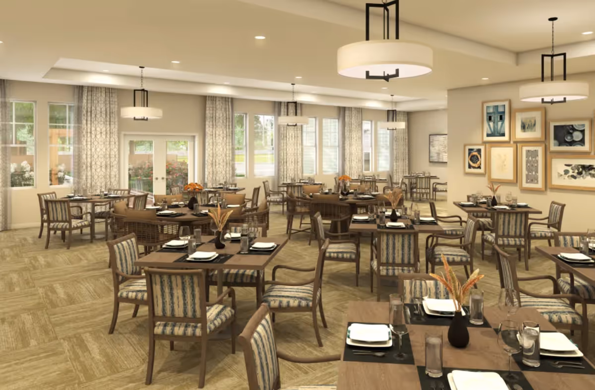 Bright, spacious dining room with multiple set tables and chairs, pendant lights, and wall art.