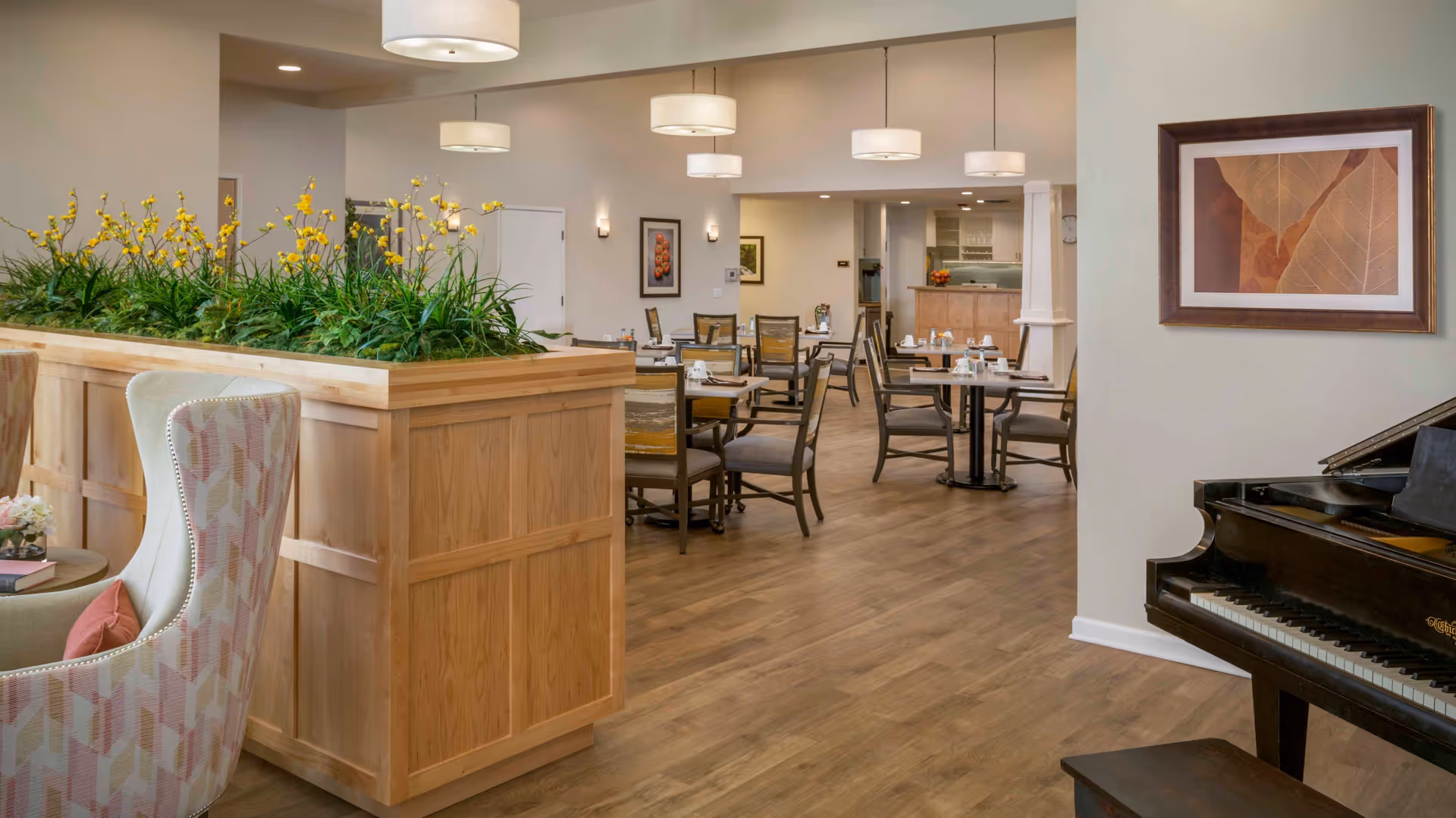 Open dining area with multiple tables and chairs, a grand piano, and a wooden planter divider next to upholstered seating.
