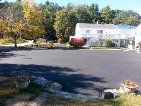 Harmony Homes by the Bay exterior: white two-story building with parking lot and trees.