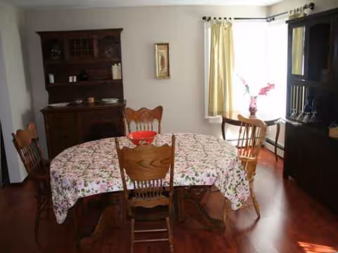 Round table with floral tablecloth and wooden chairs in a dining room