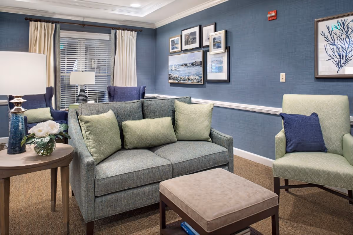 Cozy seating area with a loveseat, armchairs, ottoman, side table and artwork on blue walls.