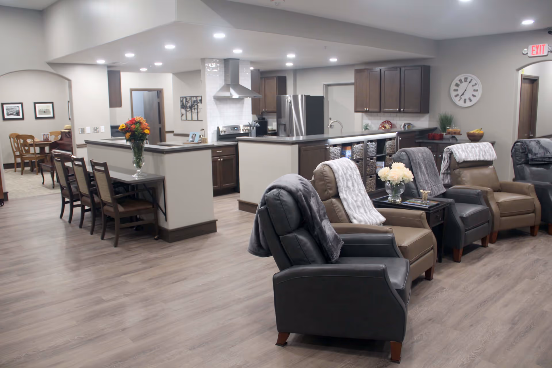 Interior view of ComfortCare Homes West lounge with recliners, sofas, and a kitchen island.