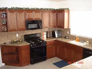 A kitchen featuring wooden cabinets, black appliances, and beige countertops.