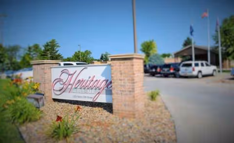 Front entrance sign reading Heritage of Bel-Air beside brick pillars and a parking lot.