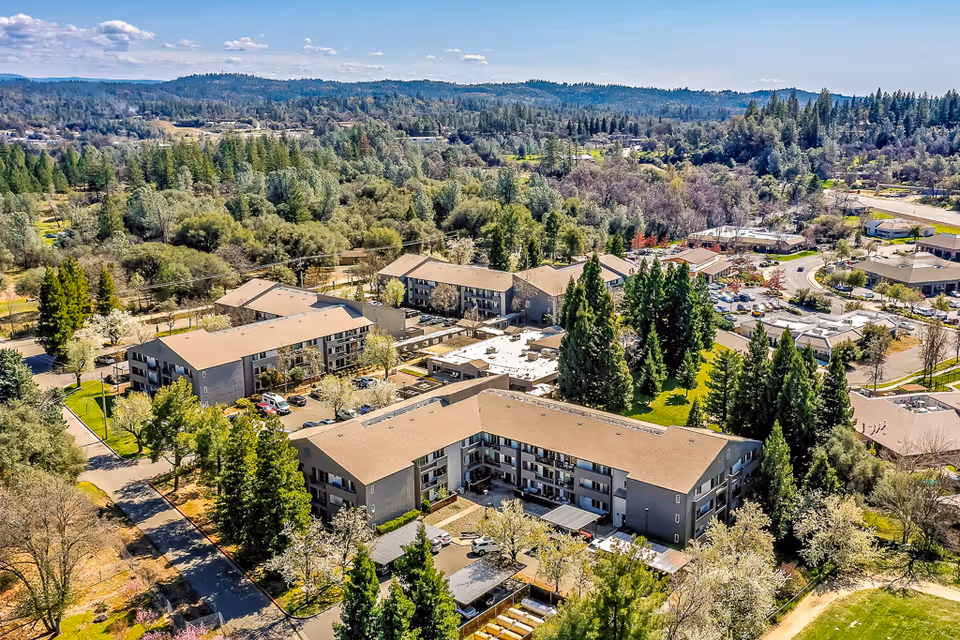 Aerial view of a multi-building senior living campus surrounded by trees.