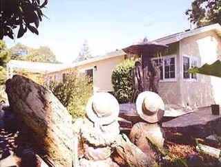 A single-story light-colored building exterior with two stone statues and surrounding landscaping.
